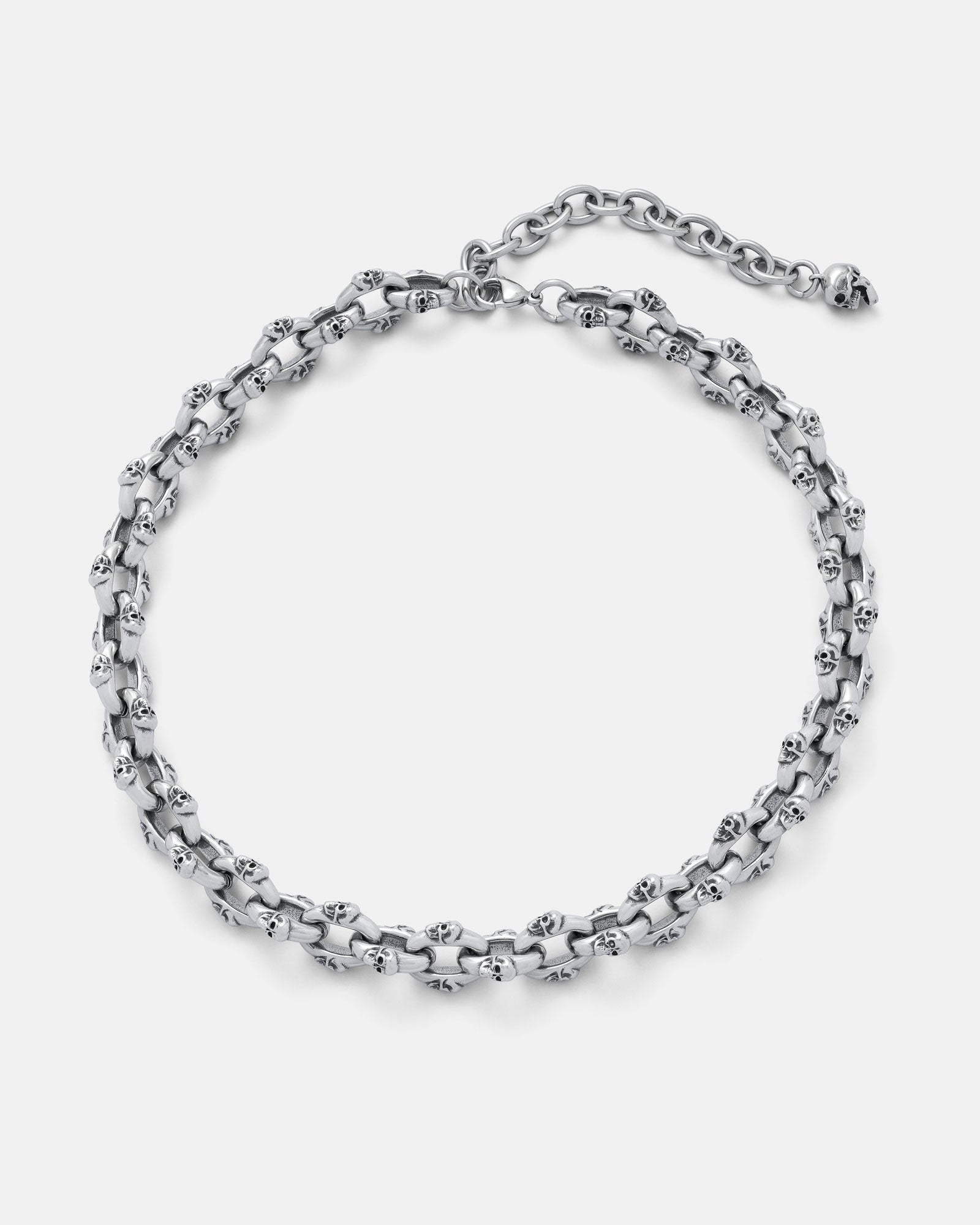 The "Boneyards" Skull Chain is a stainless steel necklace with interlinked skull-shaped links, an adjustable clasp, and extension chain, shown on a plain light background.