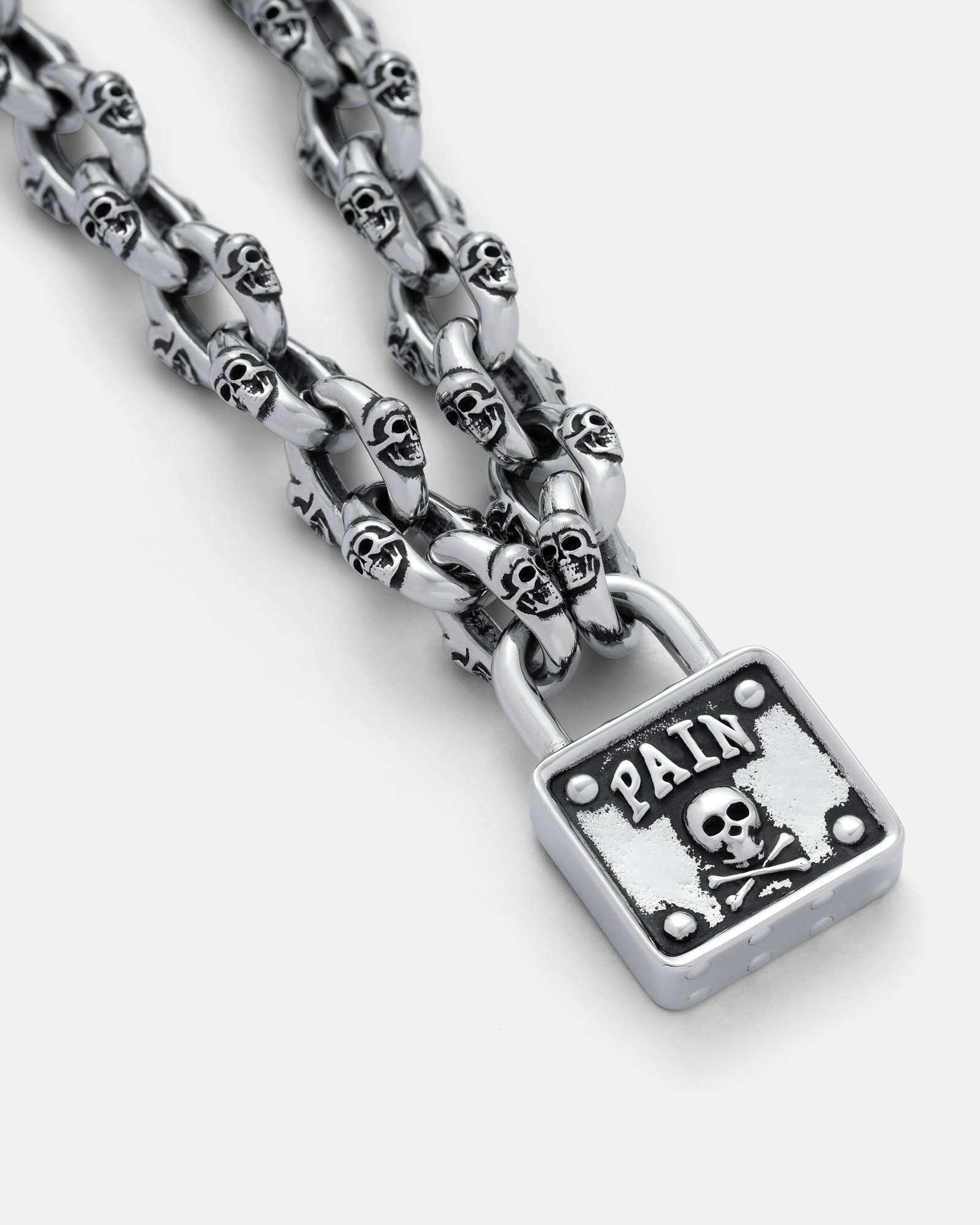 The "Boneyards" Skull Padlock Chain features bold skull-shaped links on a 12mm cable chain and a square pendant engraved with PAIN and a skull and crossbones motif.