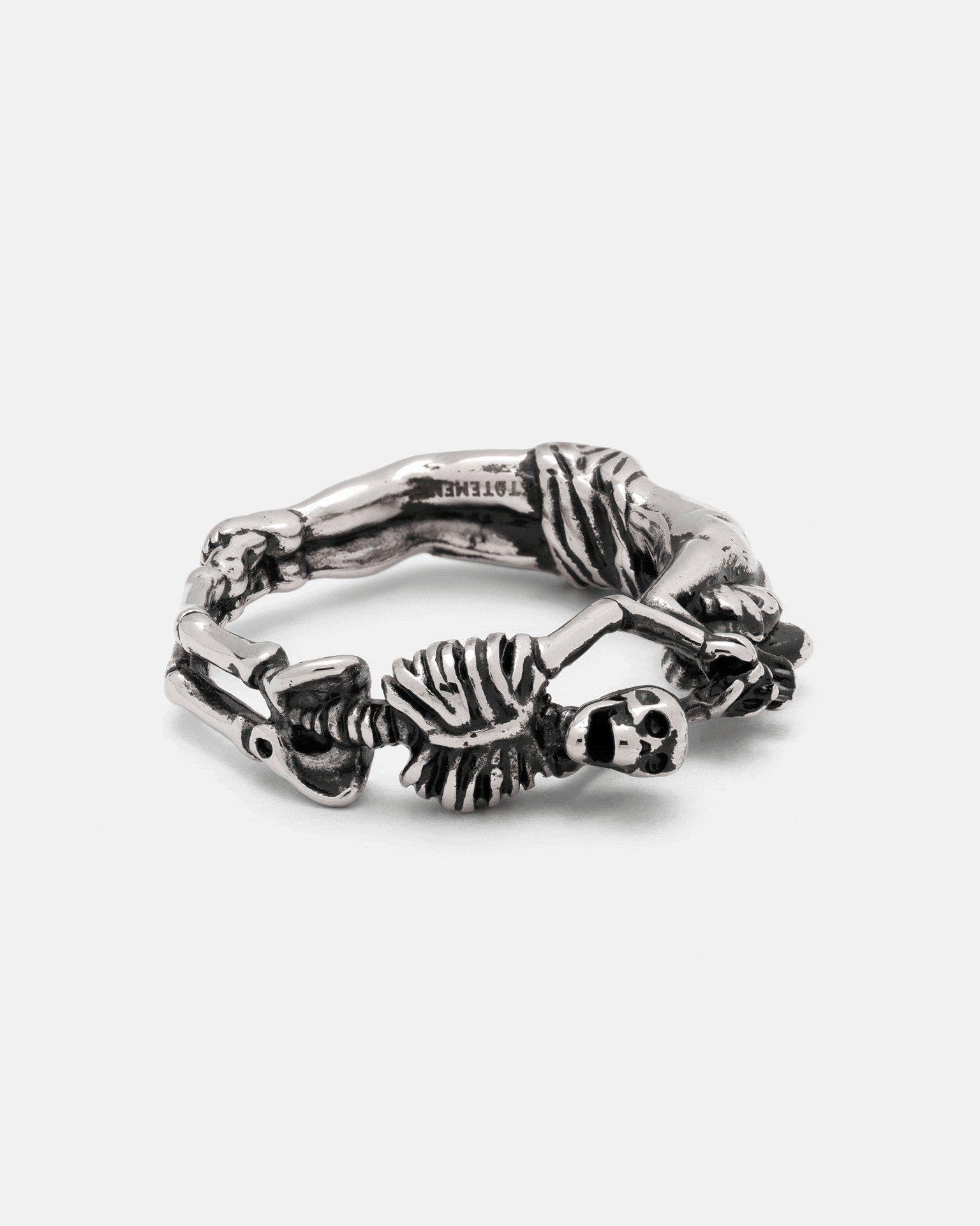 A silver Breaking Wheel Ring shaped like two interconnected human figures.