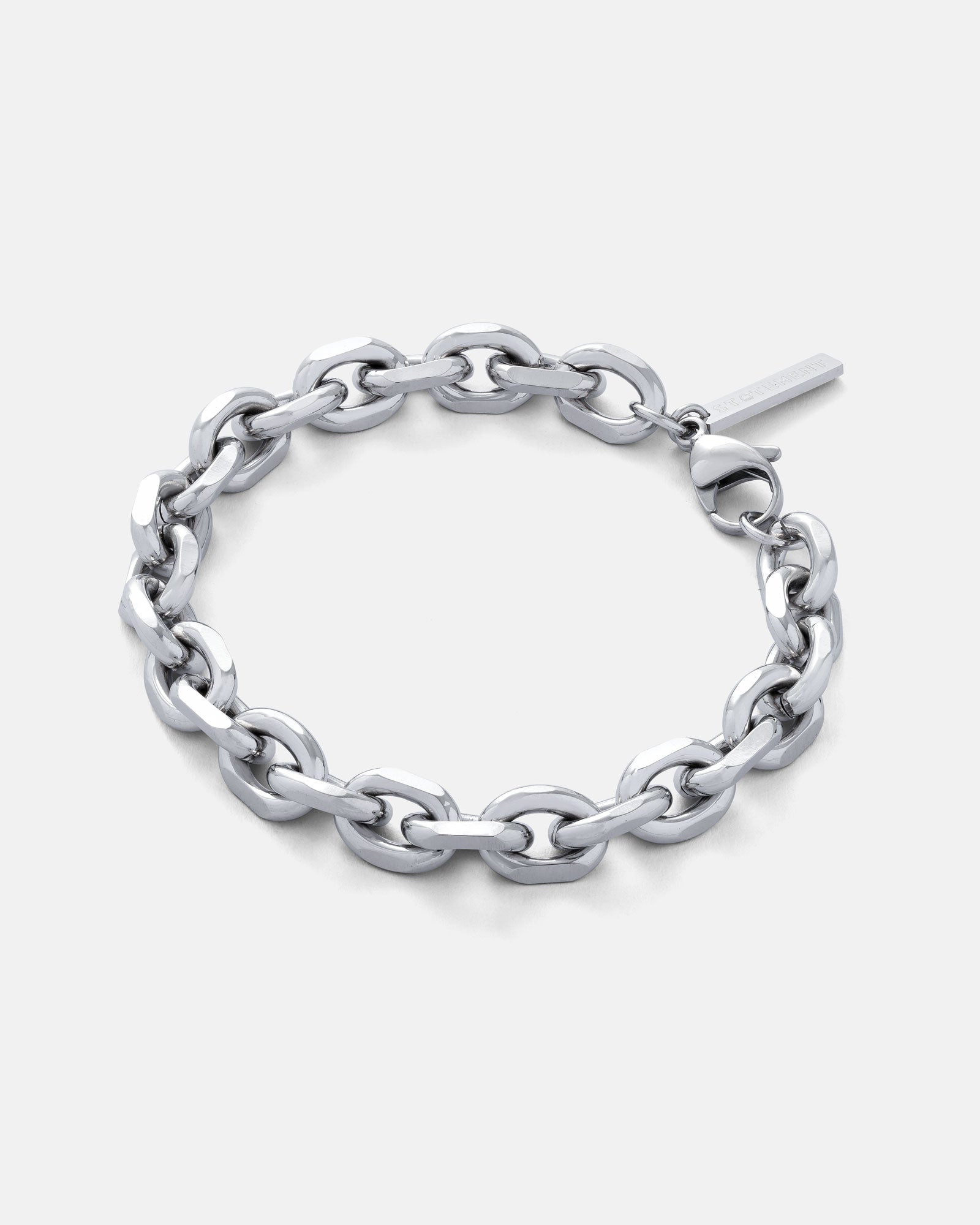 10mm cable link bracelet in silver with branded tag on clasp by statement collective on grey background.