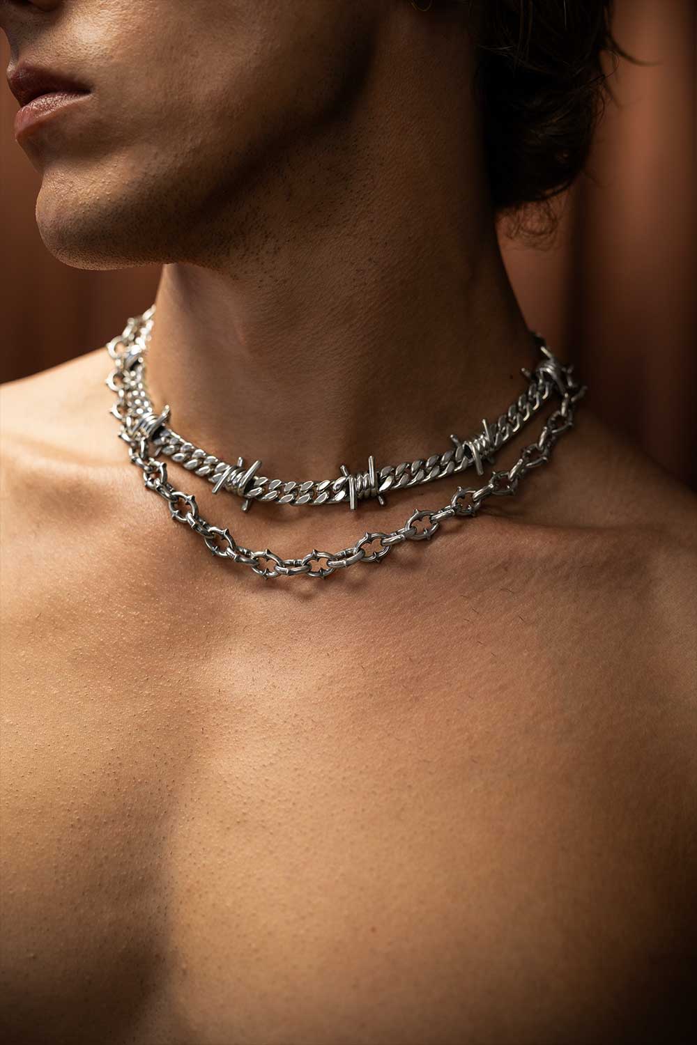Close-up of a person wearing a silver chain necklace with a blurred background