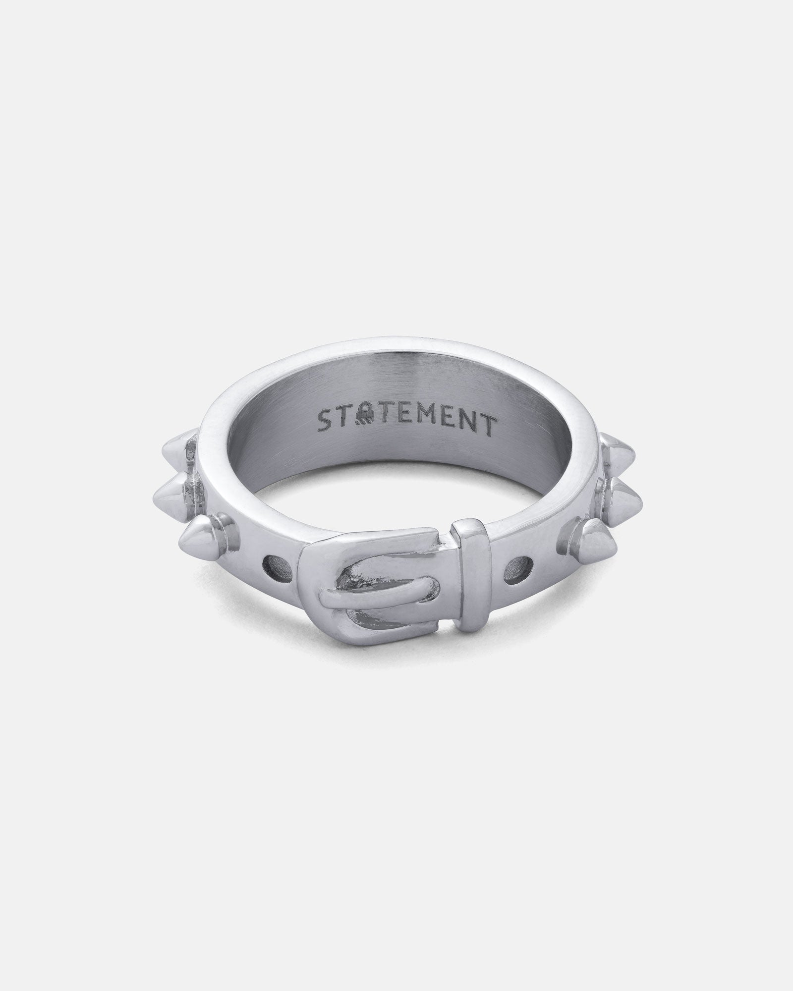 The Spiked Dog Collar Ring is a silver stainless steel ring styled like a belt with buckle and stud accents, small spikes around the band, and "STATEMENT" engraved inside—a striking goth jewelry piece.