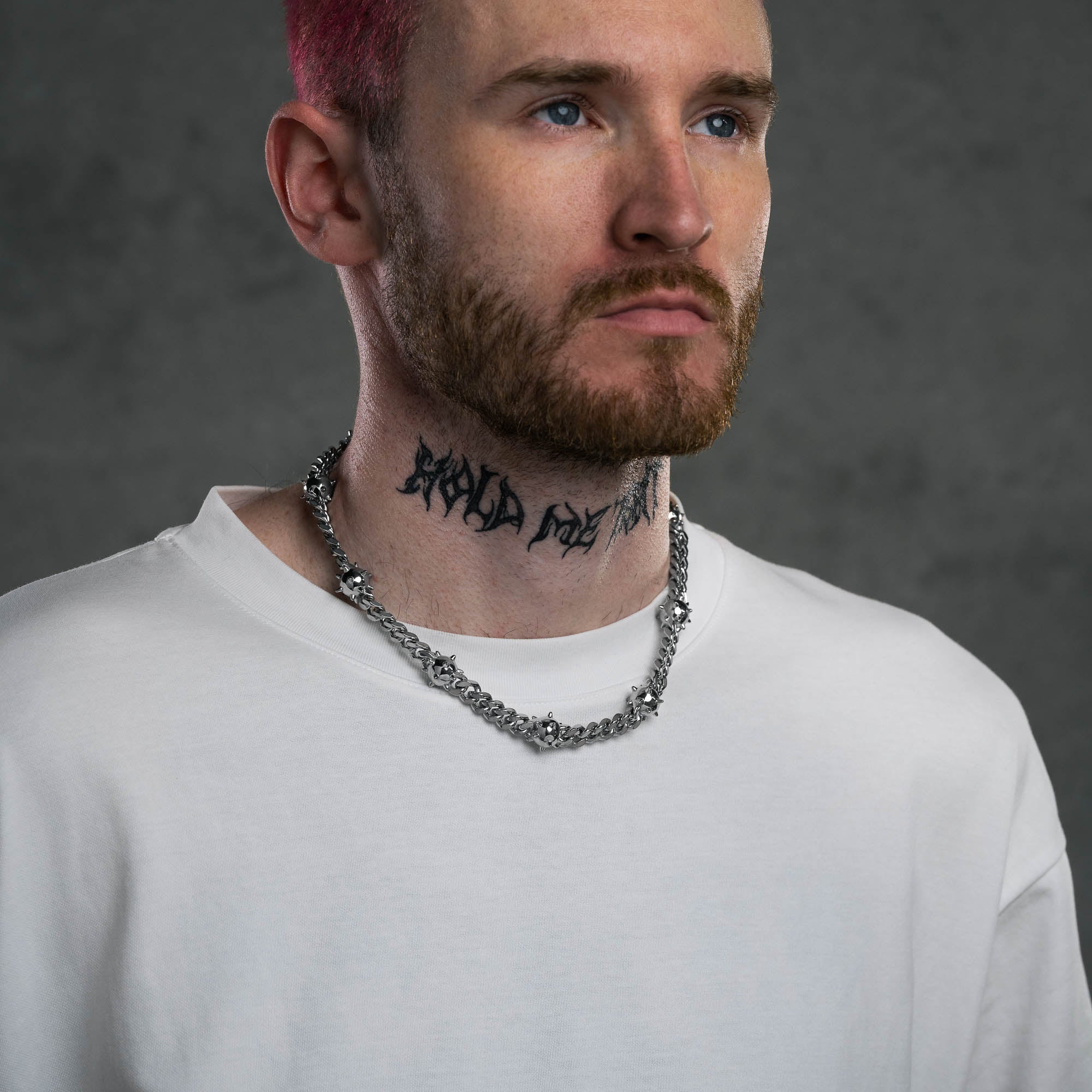 Silver Cuban Chain with spiked ball links, on male model with neck tattoo.