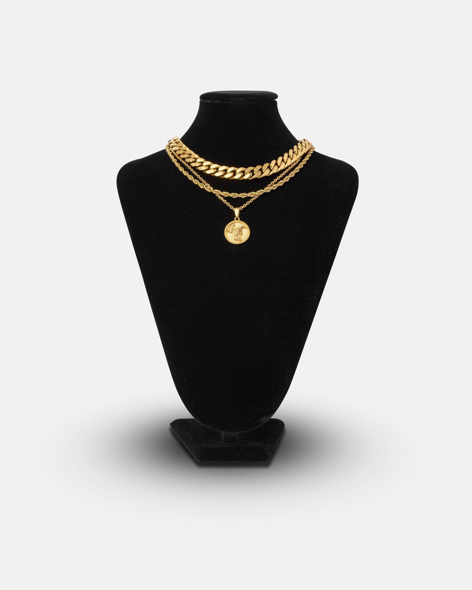 The Date Night Stack (Gold) features two gold chains—a thick Cuban link and a thinner 18k gold necklace with a round pendant—displayed on a black velvet necklace stand.