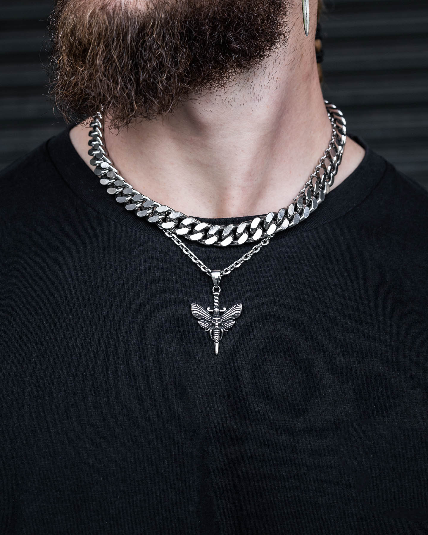 Wearing a thick silver chain and the Death's Head Moth Pendant over a black shirt, only the lower half of the face and neck are shown, evoking subtle Silence of the Lambs jewelry vibes.