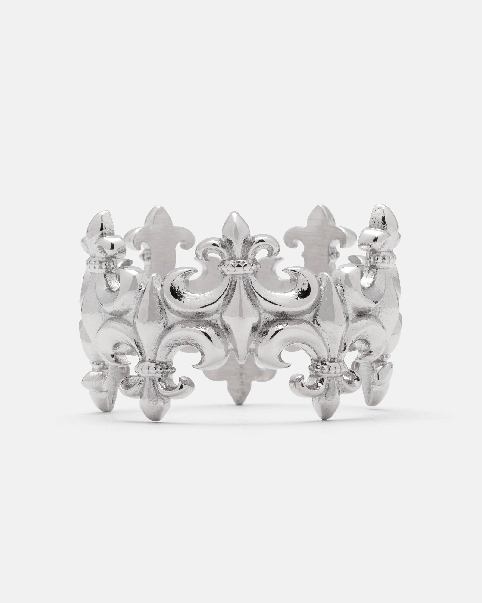 The “Crested” Fleur De Lis Ring by Statement Collective is a silver ring adorned with an ornate fleur-de-lis pattern, showcasing raised decorative features, intricate detailing, and a crown-inspired band for an elegant touch.