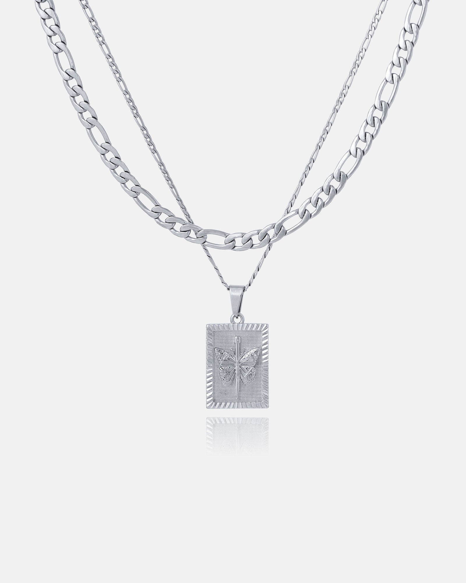 The Figaro Set (Custom Pendant Choice) features two layered silver chains: a flat curb chain and a thinner Figaro chain with a rectangular pendant displaying a raised butterfly design, shown on a plain white background.