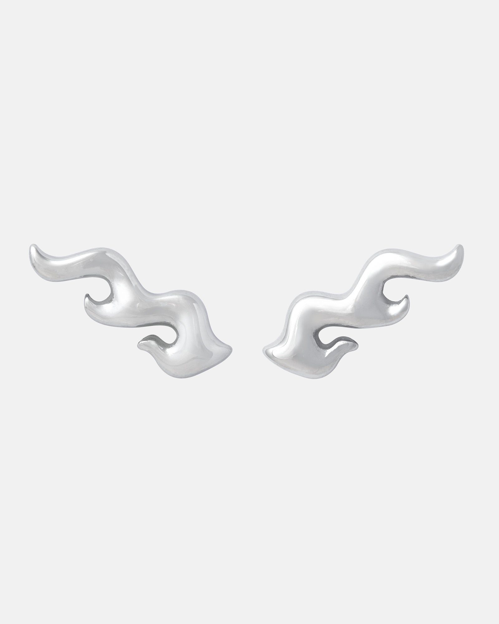 Pyro" Flame Earrings feature a mirrored double-flame design for a modern, artistic look. Crafted from hypoallergenic stainless steel, they are shown on a plain light gray background.