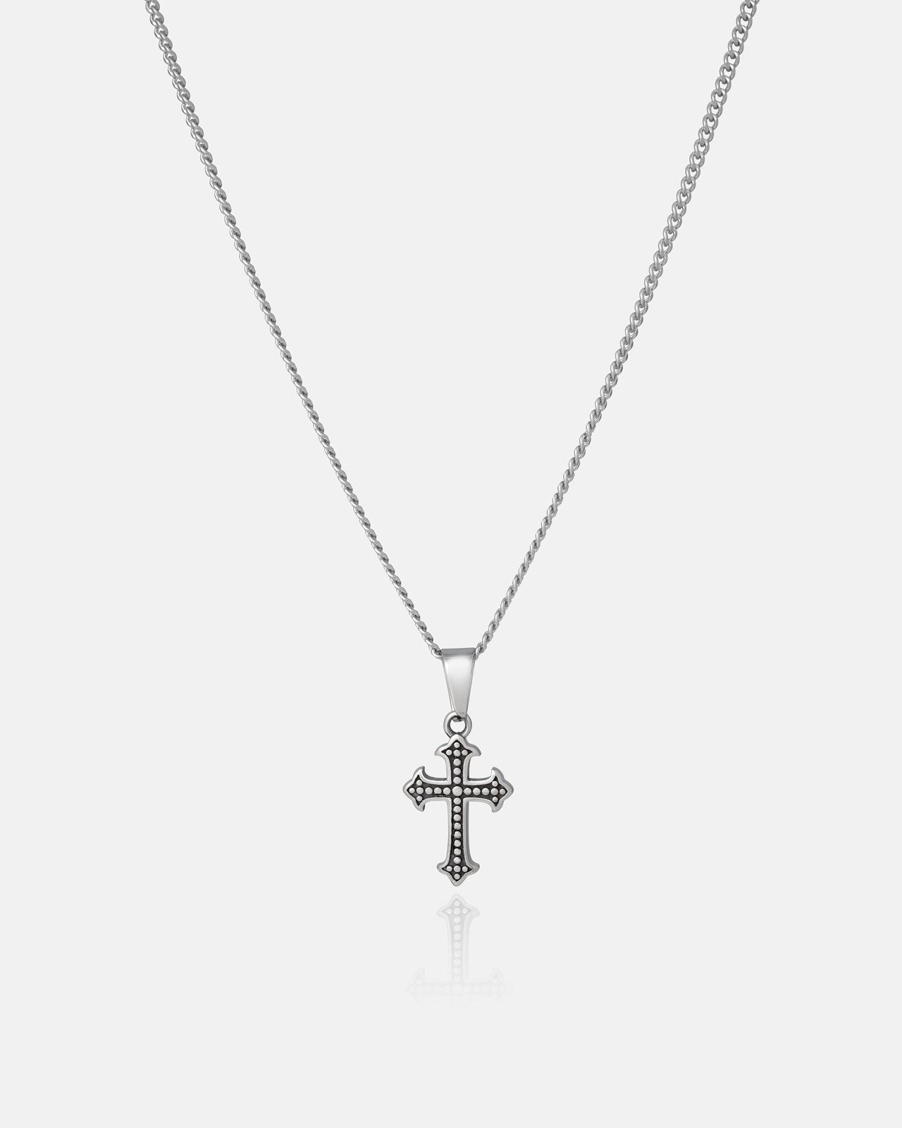 The Statement Collective French Cross Pendant features decorative accents on a detailed Cuban link chain, elegantly showcased against a plain white background.