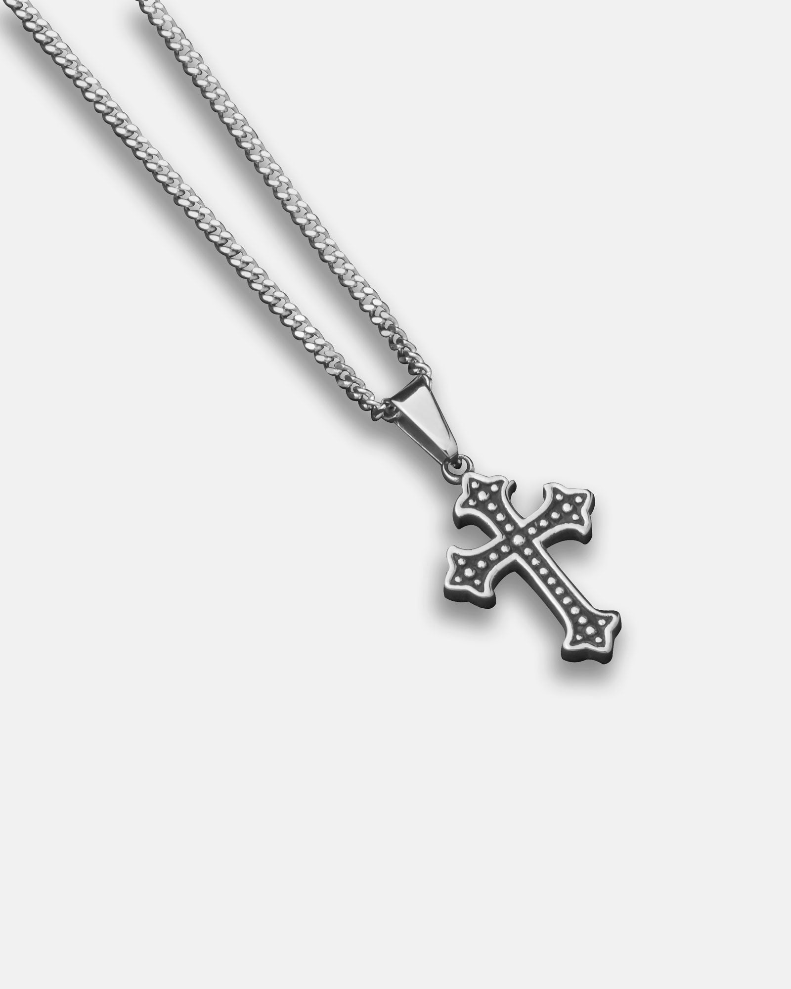 The French Cross Pendant features small dot accents and hangs from a delicate figaro chain, beautifully displayed on a white background.