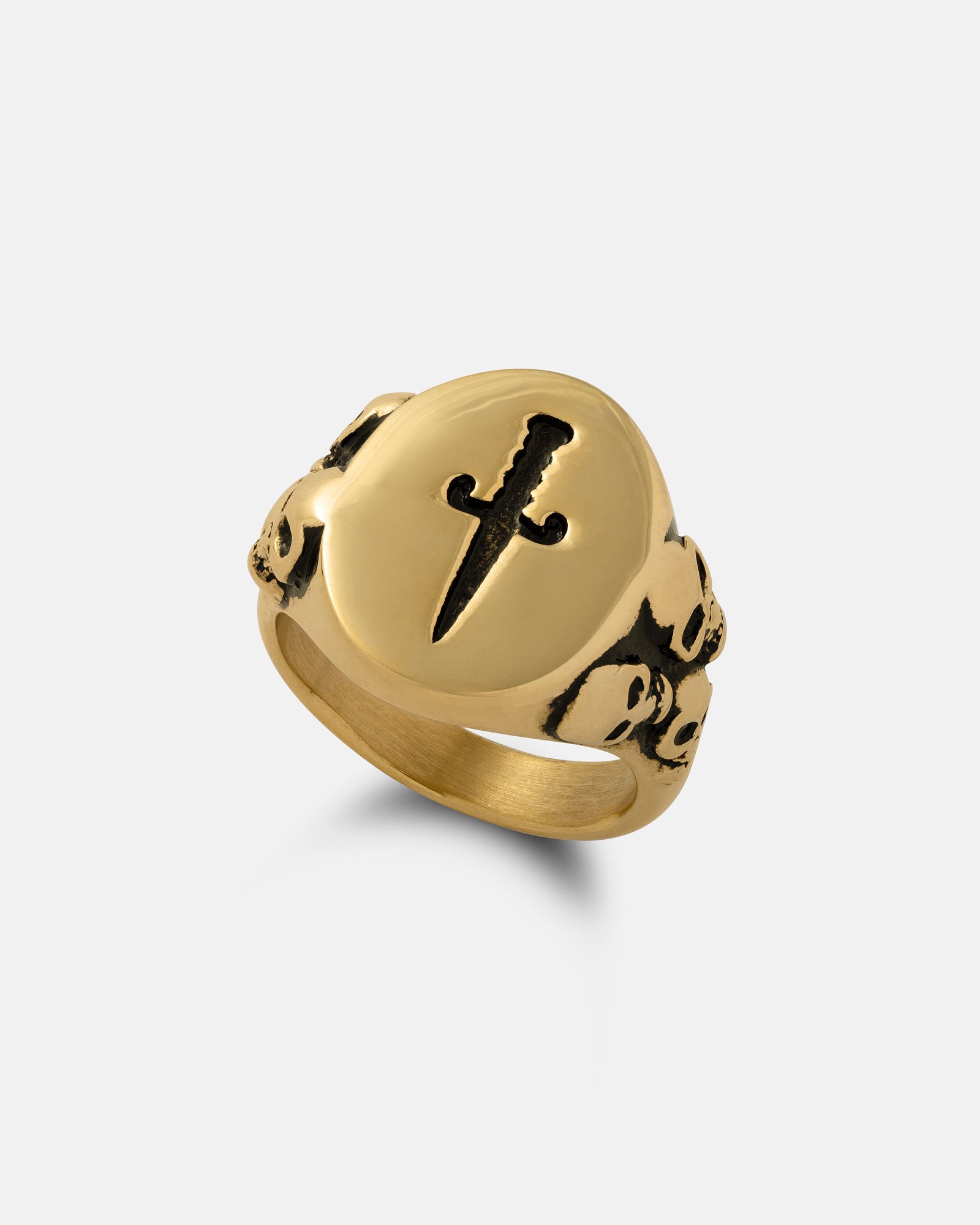 The Graveyard Signet Ring (Gold) is crafted in 18k gold with a raised dagger design on the face and small skull engravings on the sides, shown against a plain white background.