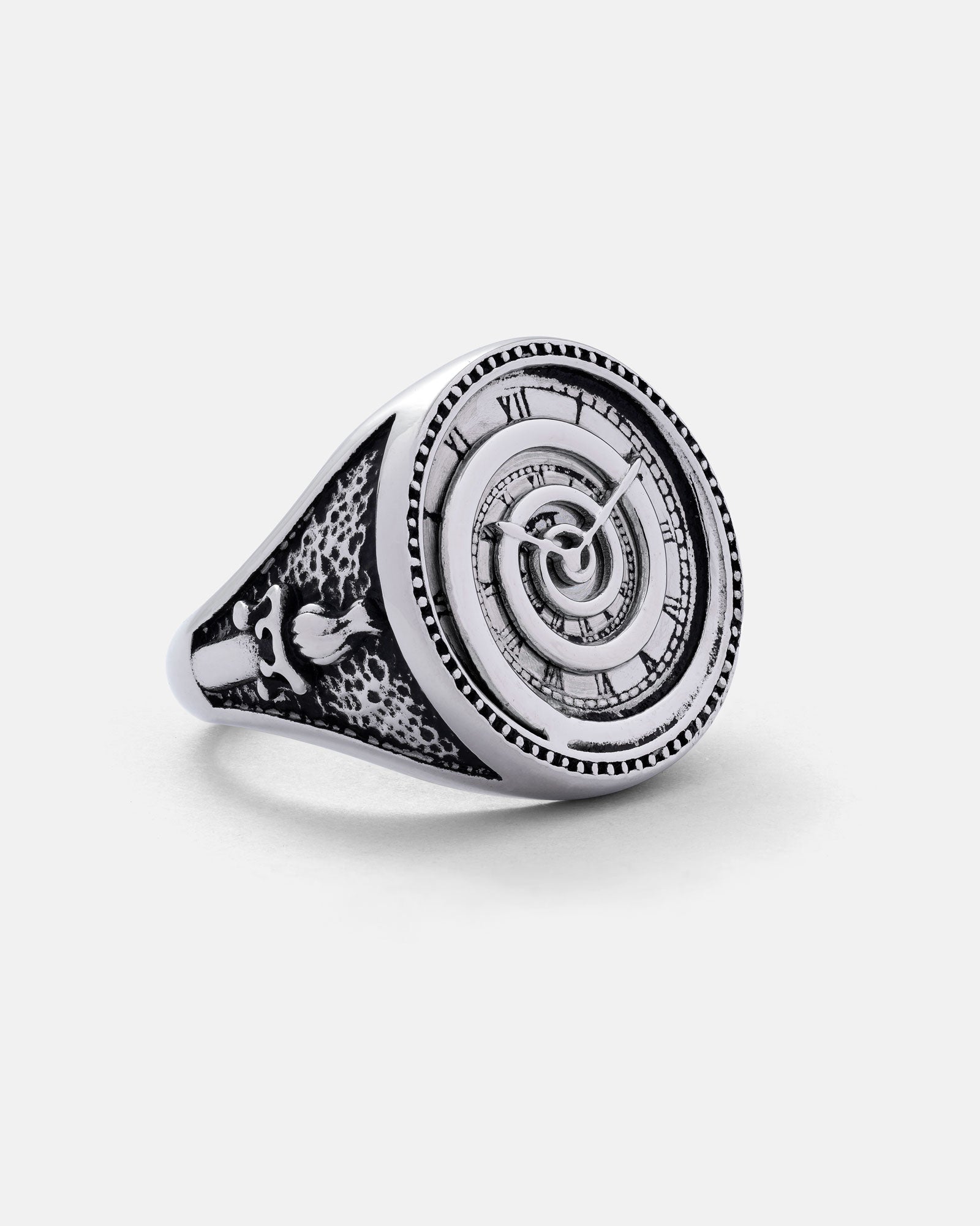 The Infinite Clock Ring is crafted in stainless steel with a spiral design, vintage clock face, and engraved winged skull on the band. Photographed against a plain white background, it features intricate jewelry detailing.