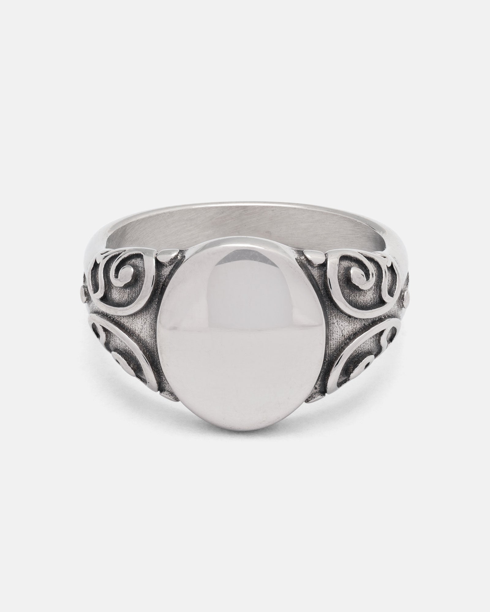 The Mini Oval Scroll Signet Ring by Statement Collective features a polished silver centerpiece and an ornate traditional scroll pattern swirling along the band, displayed on a plain white background.