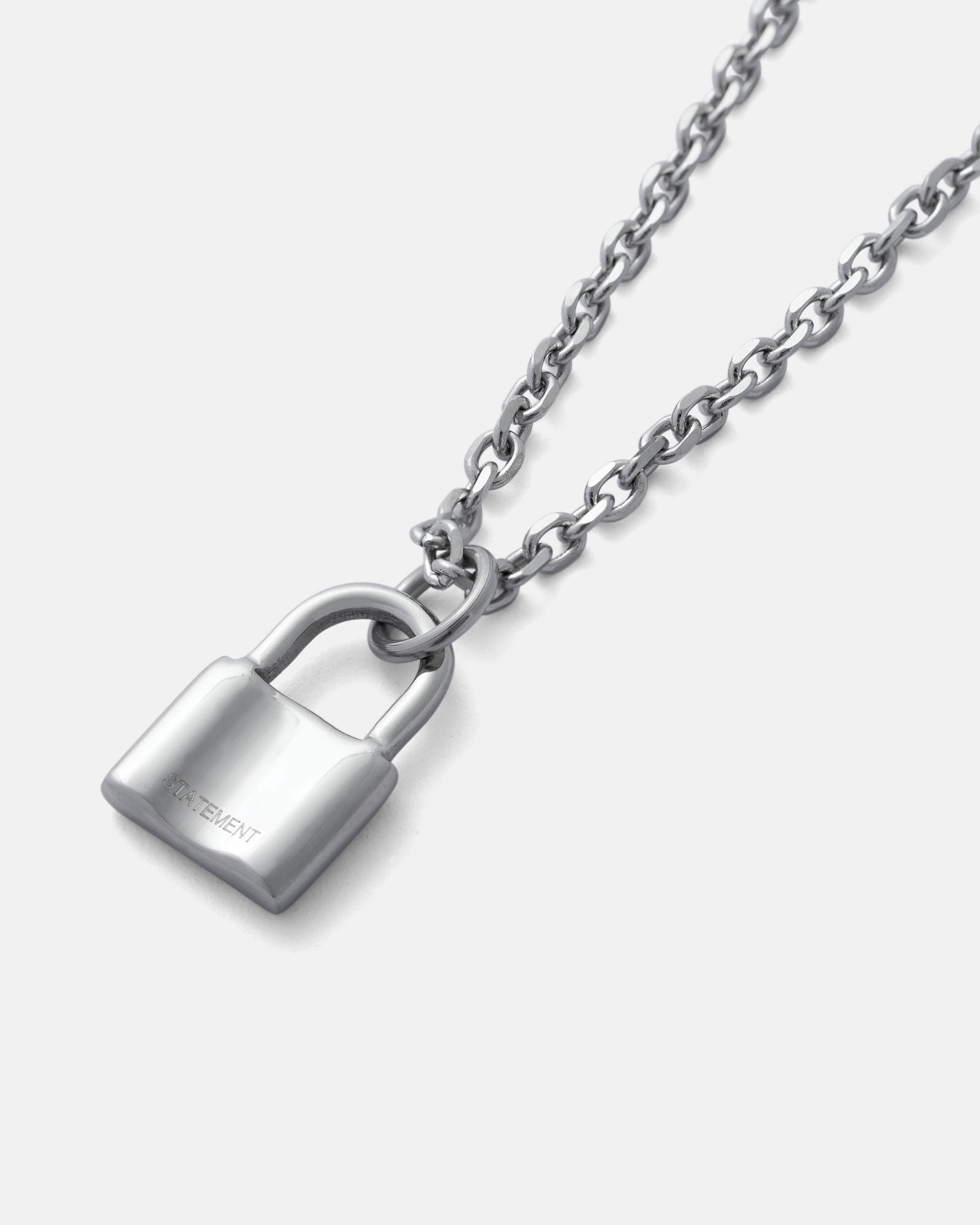 The Mini Padlock Pendant is a silver necklace with a shiny padlock charm, displayed on a plain light gray background and suspended from a delicate 2mm chain.