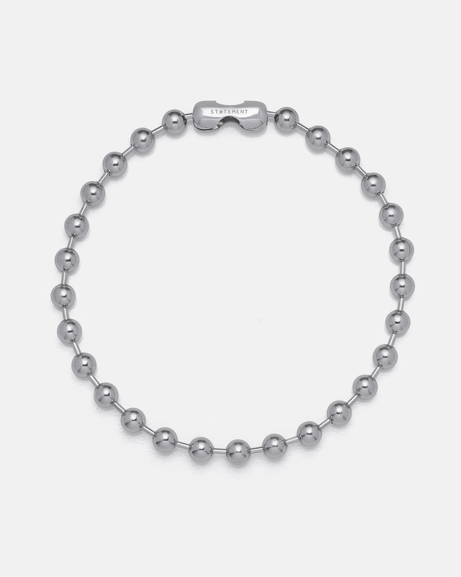 The No Tourists Choker is a silver beaded necklace with round, polished metal beads in a ball chain style and a rectangular STATEMENT-engraved clasp, shown on a plain white background.