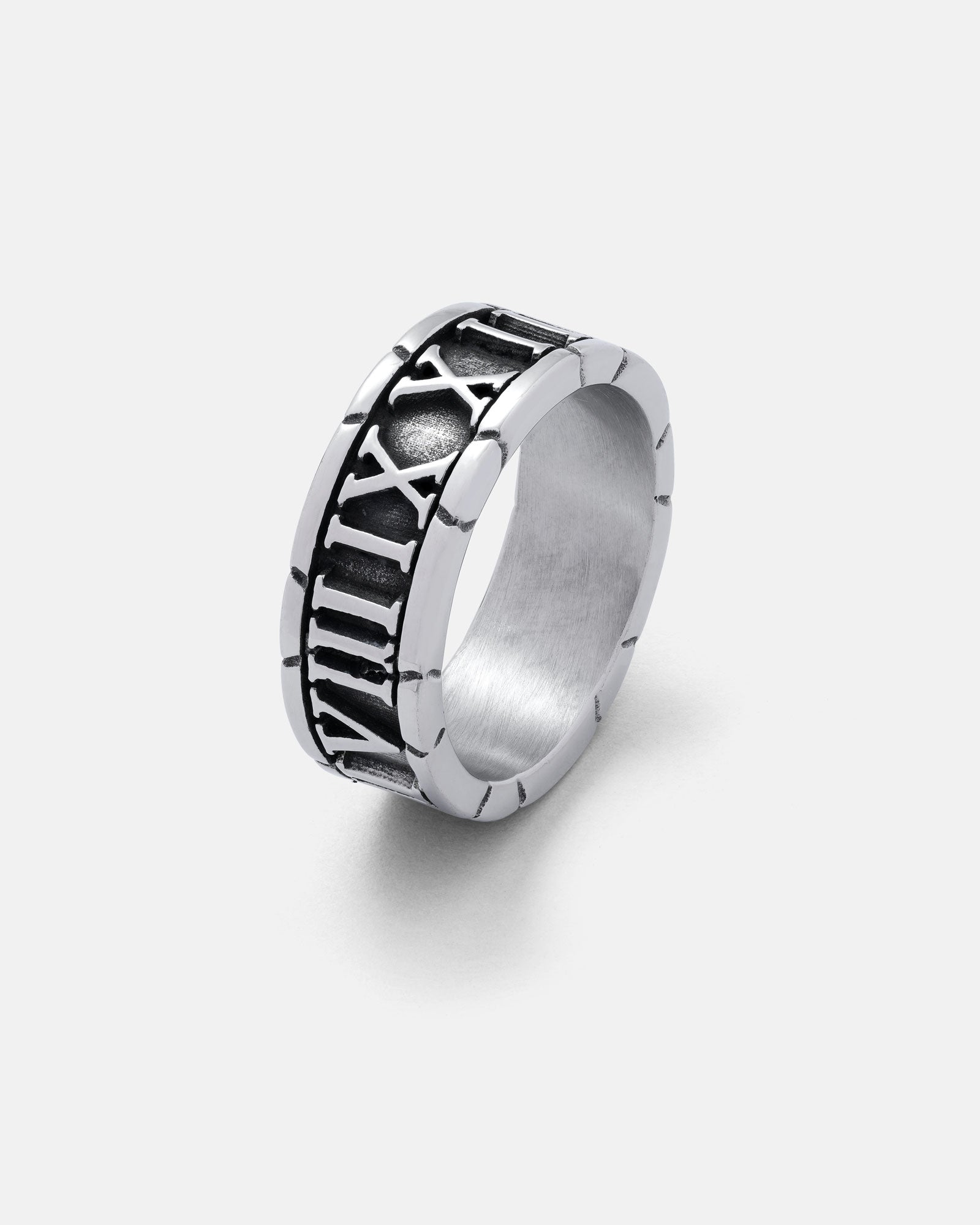 The Numerals Ring is a stainless steel band featuring raised Roman numerals on a black strip, shown against a plain white background.