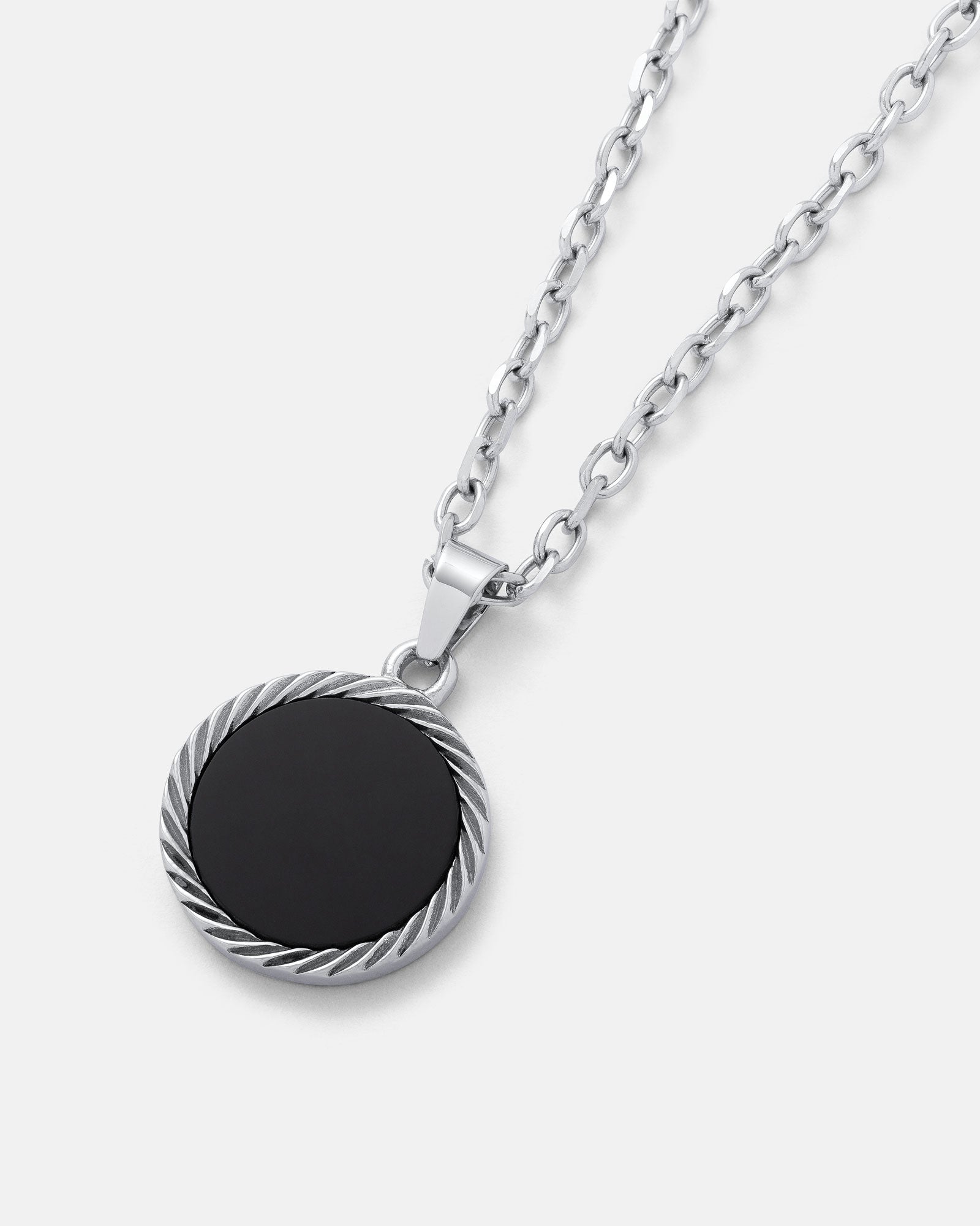The Onyx Medallion Pendant is a silver chain necklace with a round black onyx pendant bordered by a twisted rope design, shown against a plain white background.