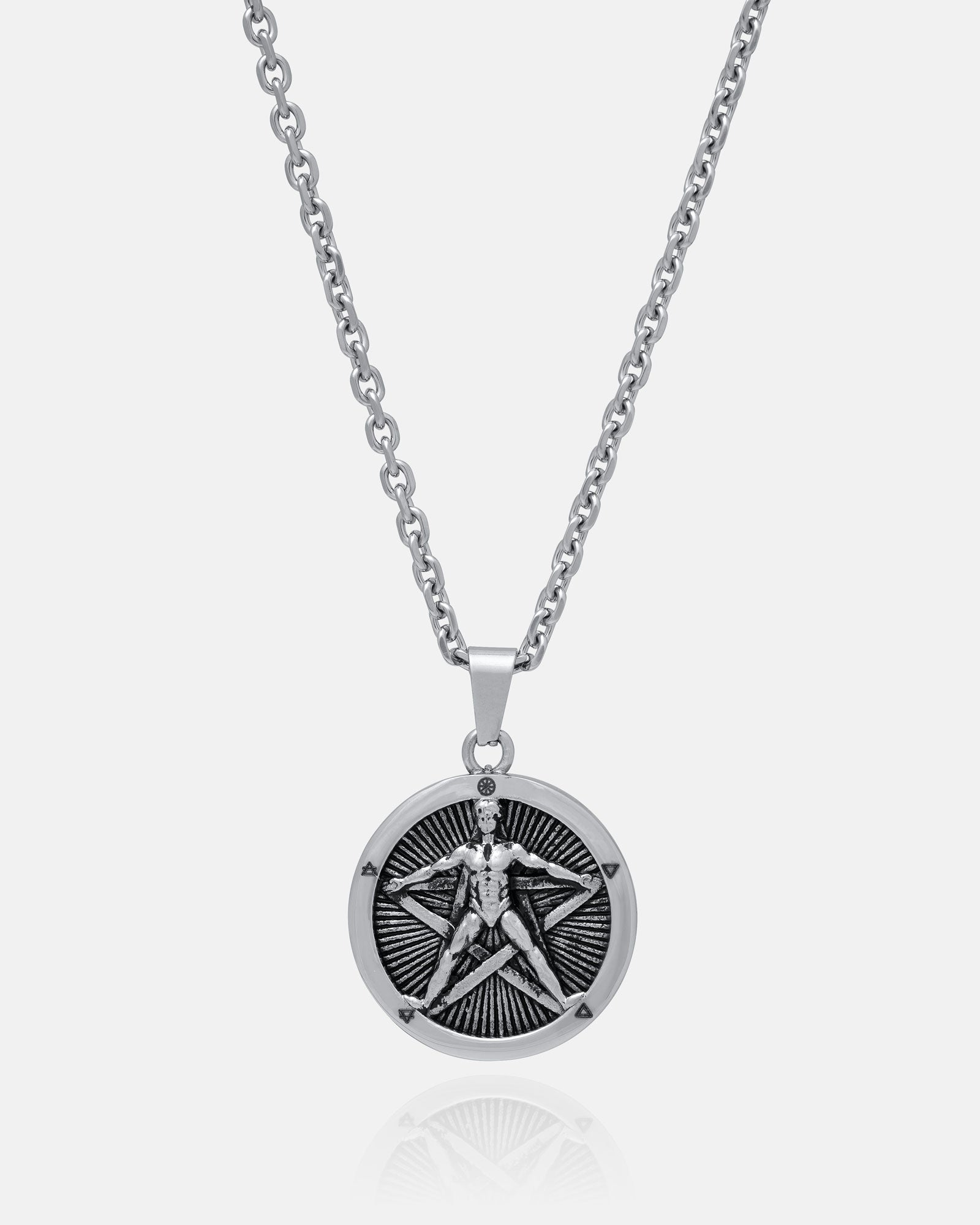 Introducing "The Star of the Magi" Pendant: a durable stainless steel necklace with a silver chain and a round pendant engraved with a Vitruvian Man-like figure against a radiant sunburst background.
