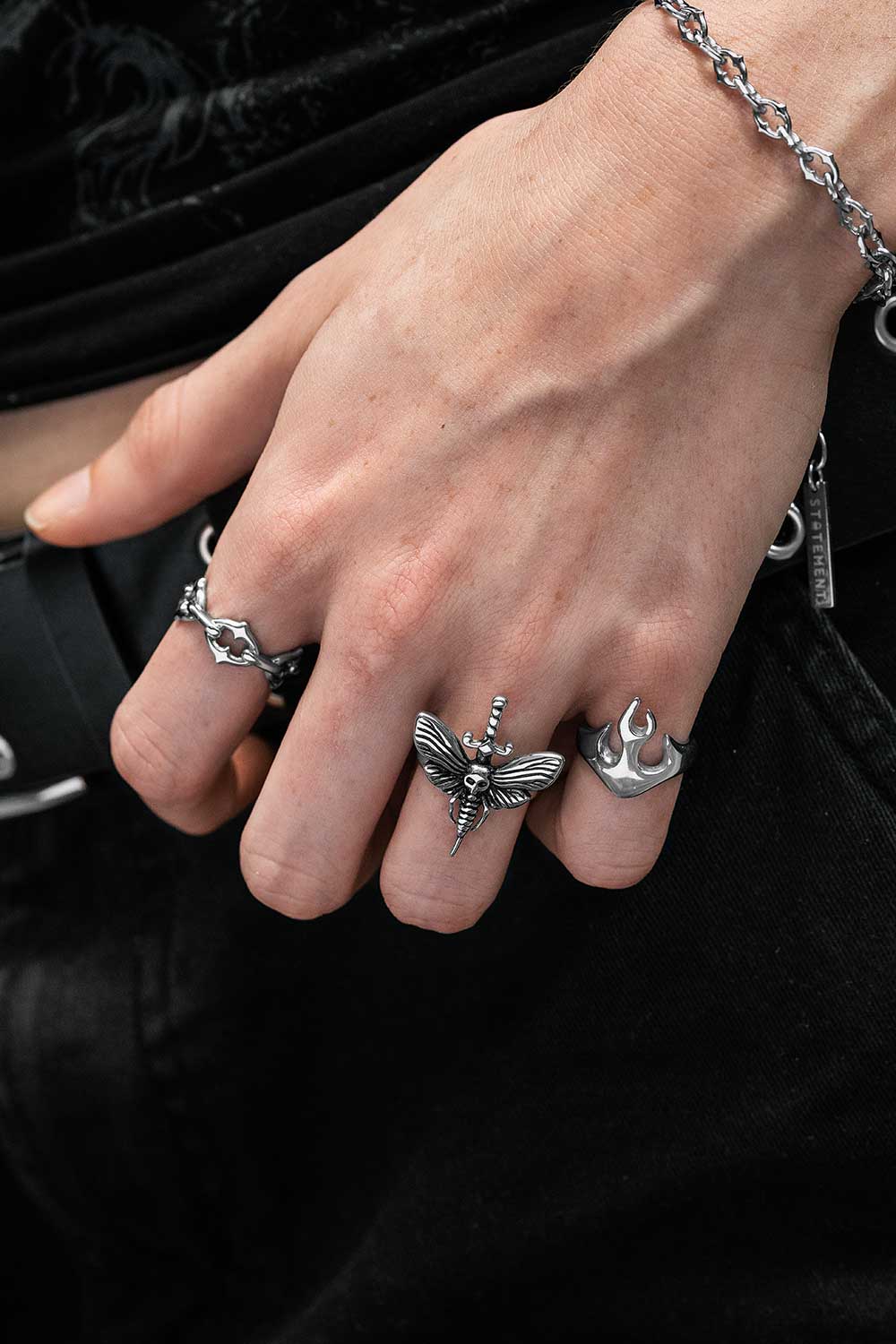 Hand wearing multiple silver rings with a dark background