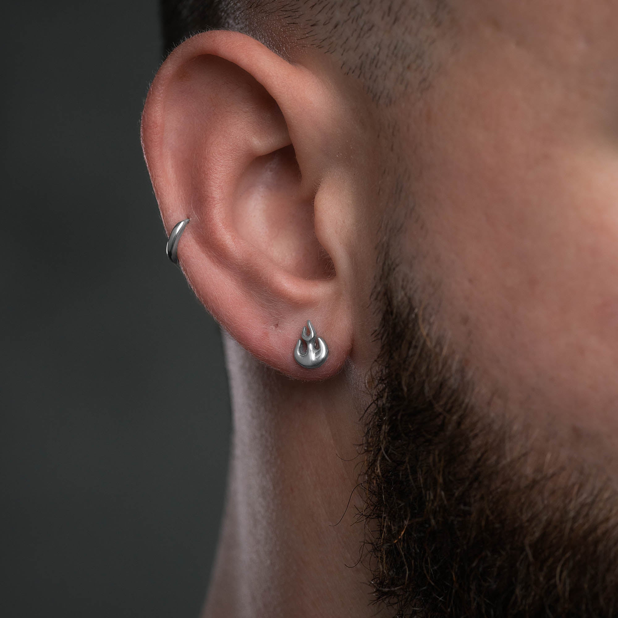 Silver flame stud earring on male model