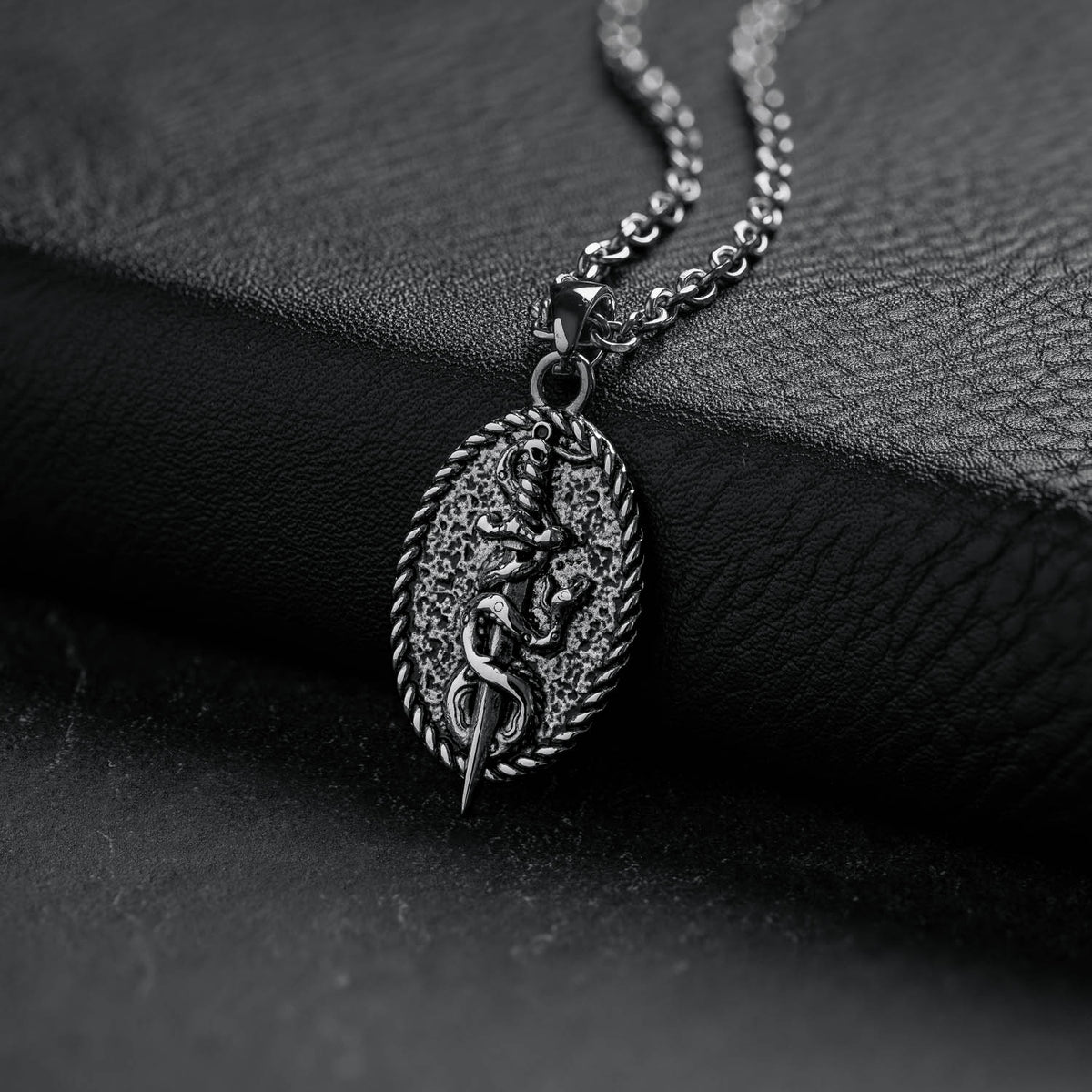 silver dagger pendant with snake on oval background