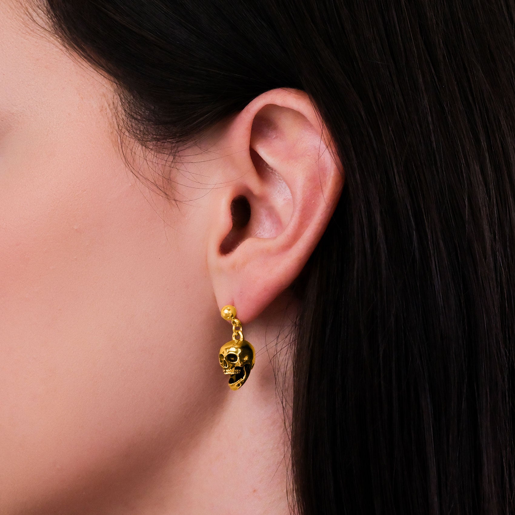 Side view of gold skull punk earrings 