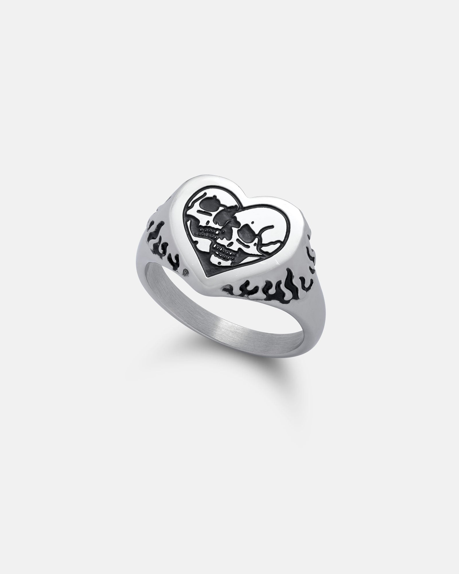 The Skull Heart Ring features a silver, heart-shaped face with two engraved skulls and black flame designs on the sides, displayed against a plain light background.