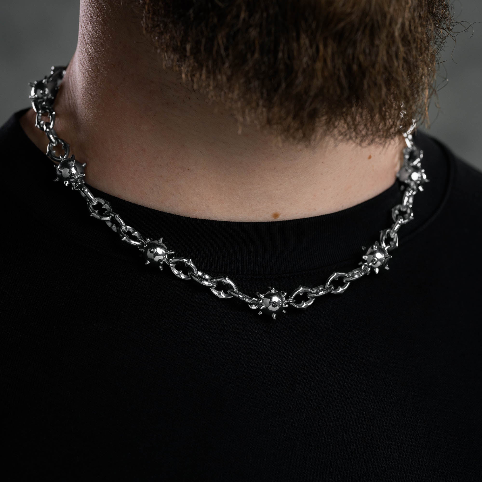 Man's neck wearing silver spiked ball necklace chain by statement collective