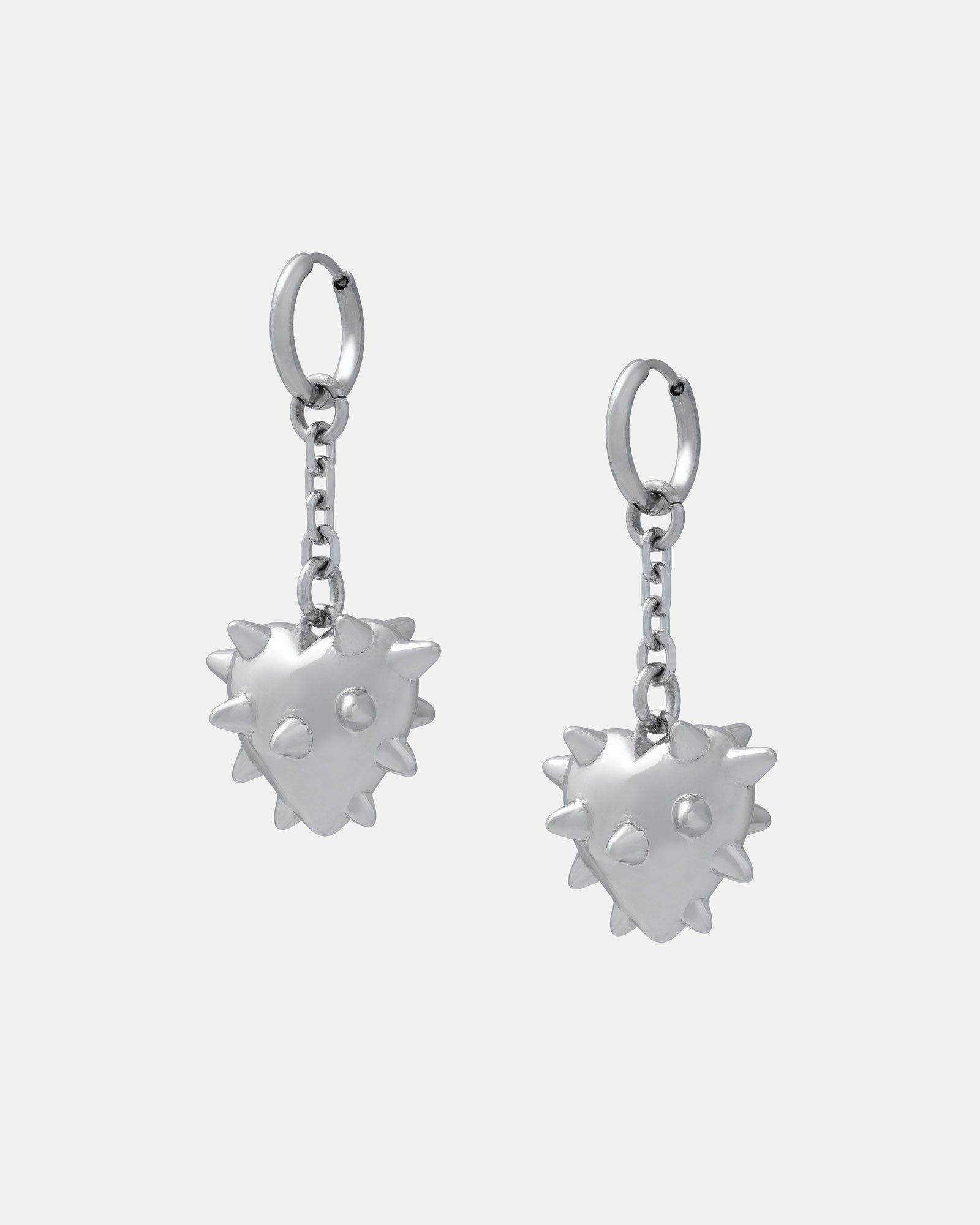 The "Love Hurts" Earring features silver hoops with spiked, heart-shaped charms that have two small indents, each hanging from a short chain against a plain white background.