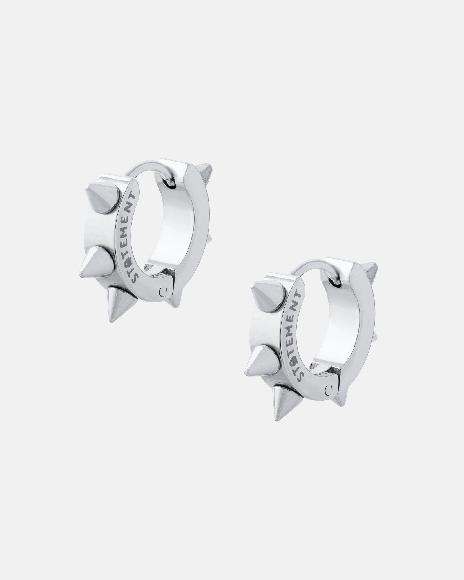 The 8mm Spiked Hoop Earrings feature three bold spikes on each huggie and are engraved with "STATEMENT" on the inner side, shown against a plain light gray background.