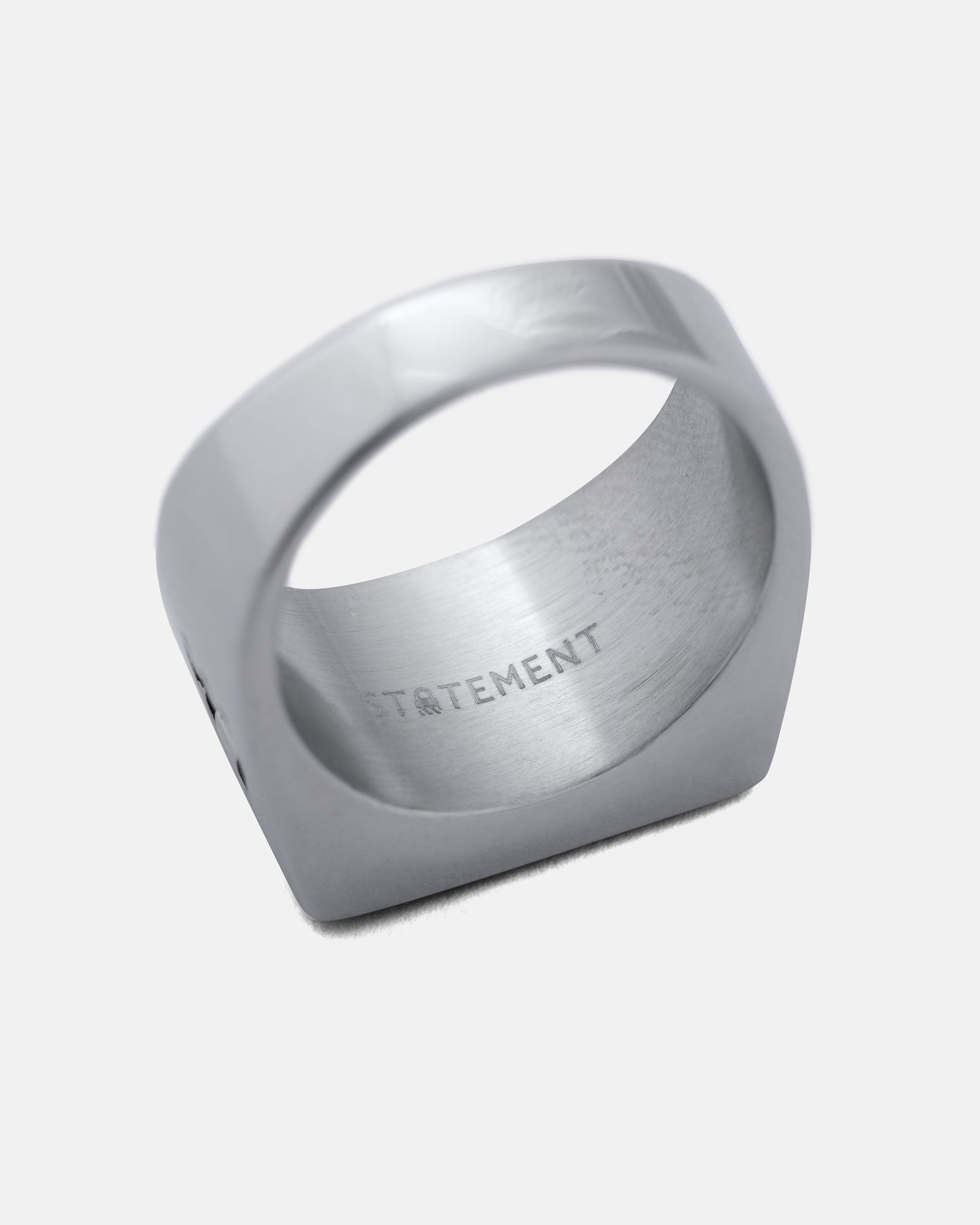 Silver signet ring with 'STATEMENT' engraving on a light gray background by statement collective