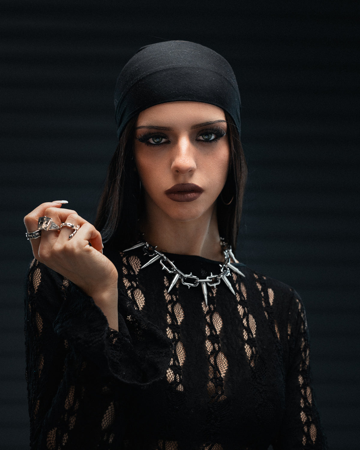 A person wearing a Sweating Bullets Necklace Chain, featuring a silver spiked choker and a heavy stainless steel chain accented with multiple silver rings.