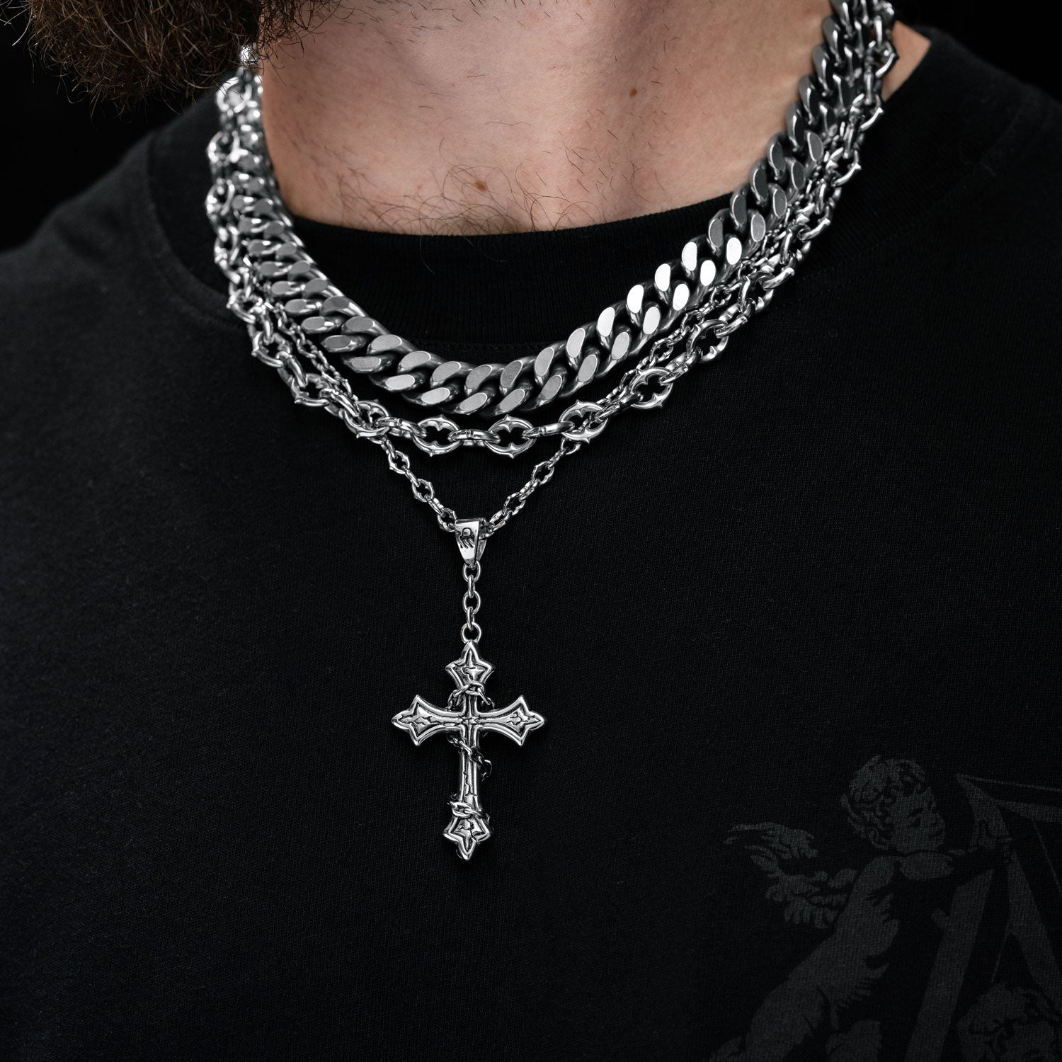 Gothic silver necklace set with spiked chain and cross pendant on mans neck by statement collective