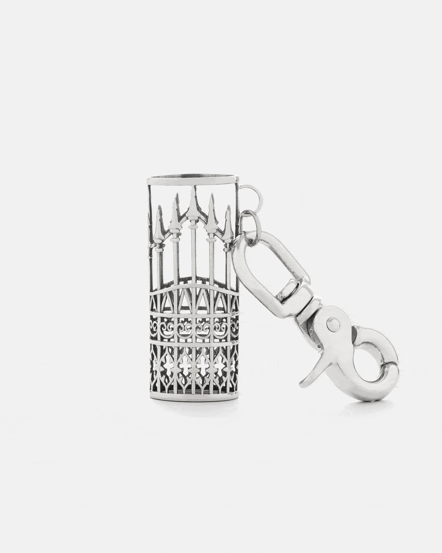 The "Wrought Iron" Lighter Sleeve by Statement Collective is a 316L stainless steel keychain charm, inspired by ornate metal gates, featuring intricate patterns and pointed tips, and comes with a large clasp.