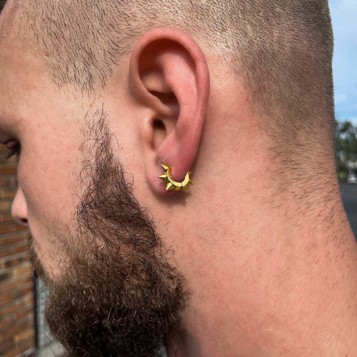 Unisex golden spiked huggy earrings on male