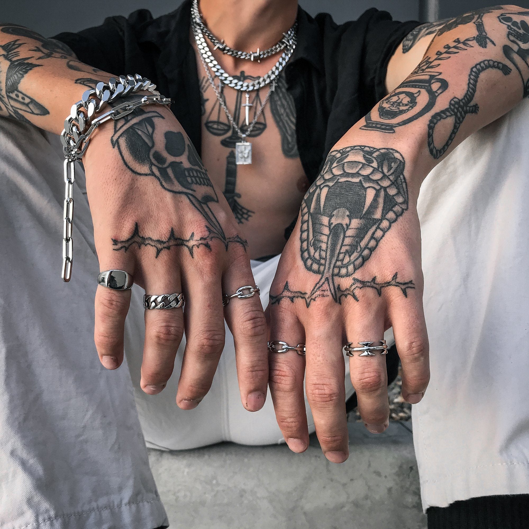 tattooed mens hands with several silver rings by statement collective