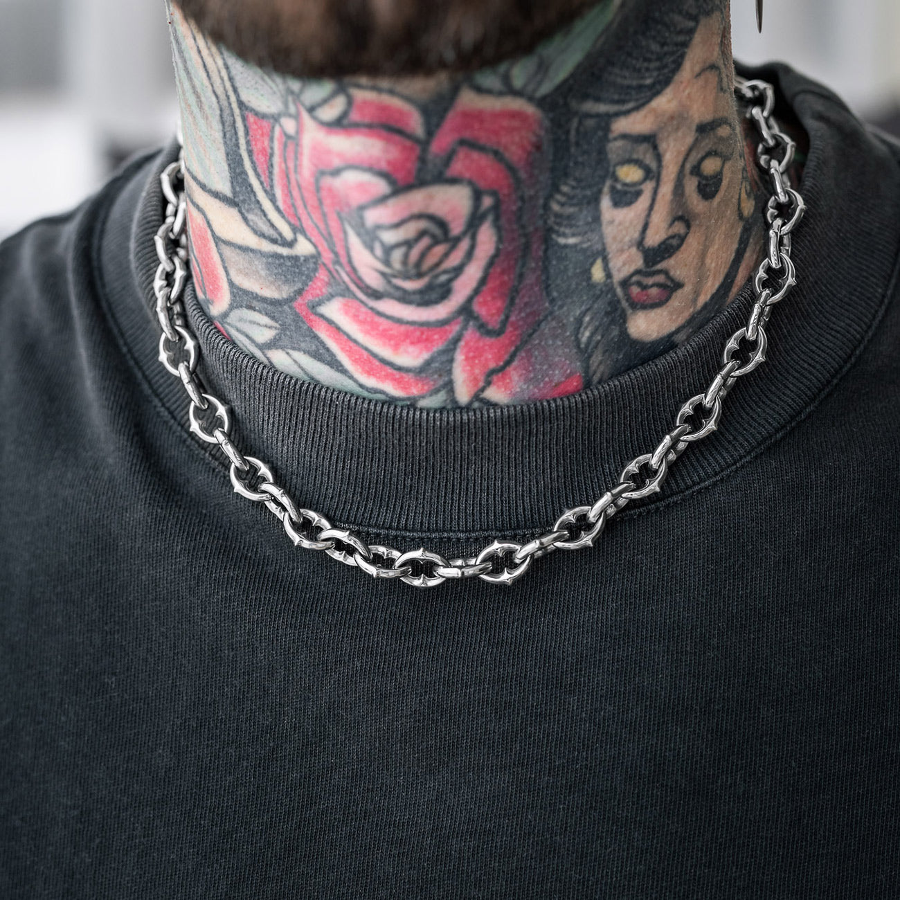 man with tattooed neck wearing gothic spiked necklace chain silver